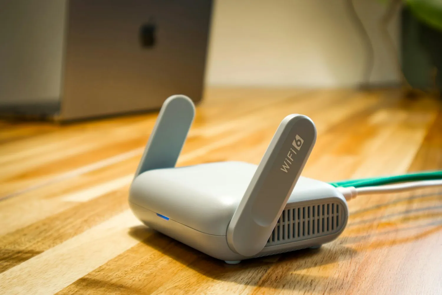 A white mesh Wi-Fi unit standing on a wooden floor beside a skirting board