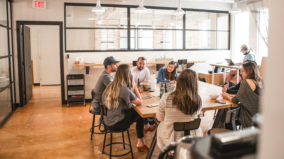 A small team meeting around a large table in a bright open-plan office
